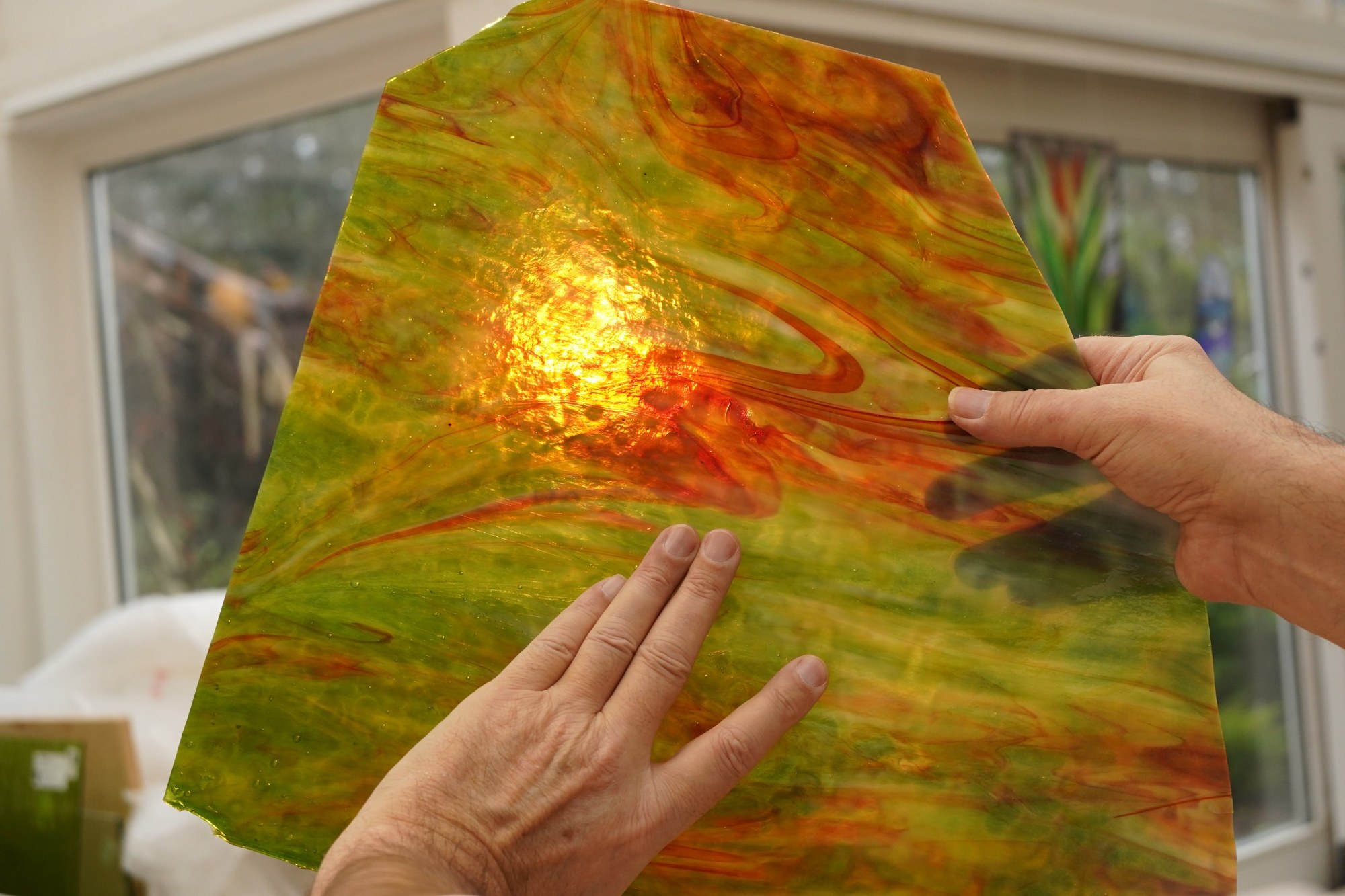 Plaque de verre vert et ambre observée devant la lumière