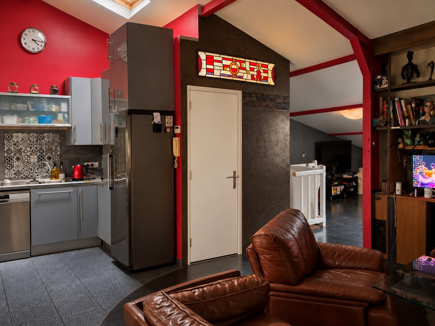 Vitrail d’imposte installé au-dessus d’une porte dans un loft aux poutres rouges