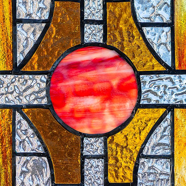 Médaillon rouge rayonnant au cœur d’une composition de verres texturés ambre et clairs