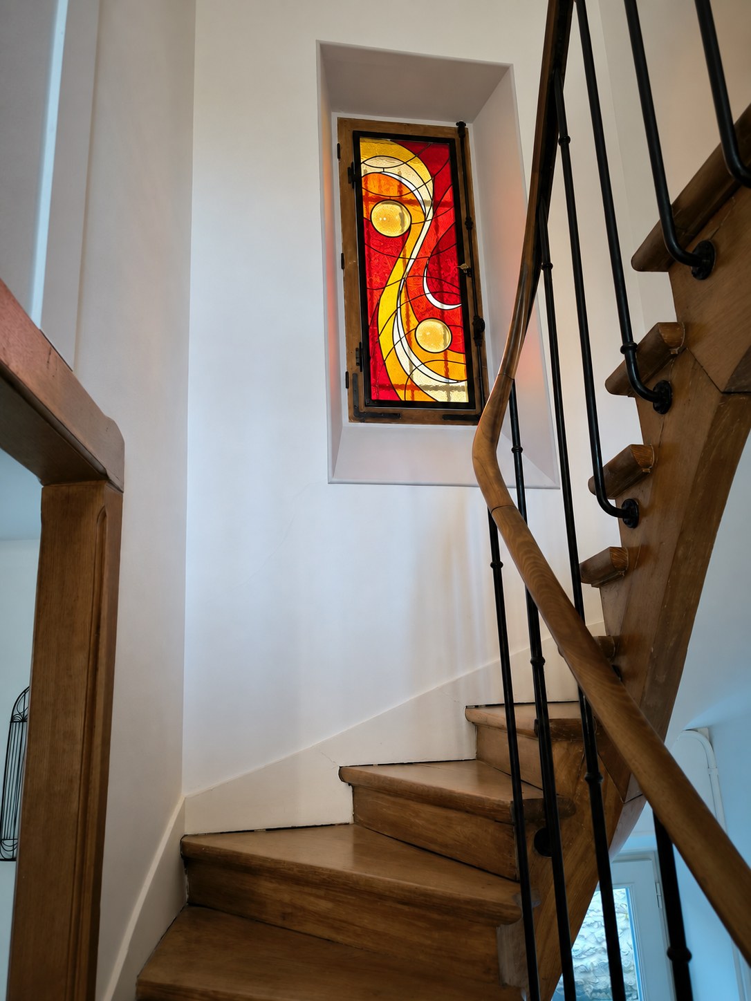 Vitrail Vibrations en rouge installé dans la fenêtre d’escalier